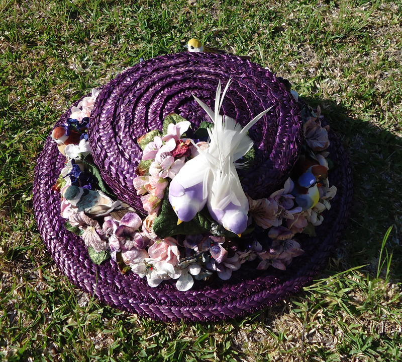 A hand dyed straw hat with velvet flowers and faux birds.