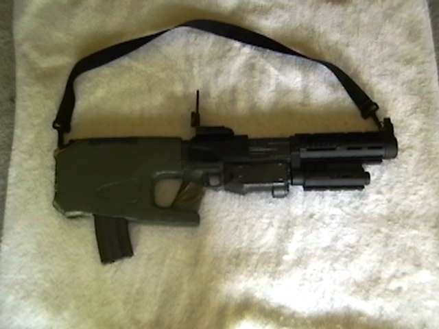 CARB weapon system in shotgun mode. Slung under the barrel is a red spot/laser designator. Magazine is not canon; it is a 30-round M16/M4 magazine.