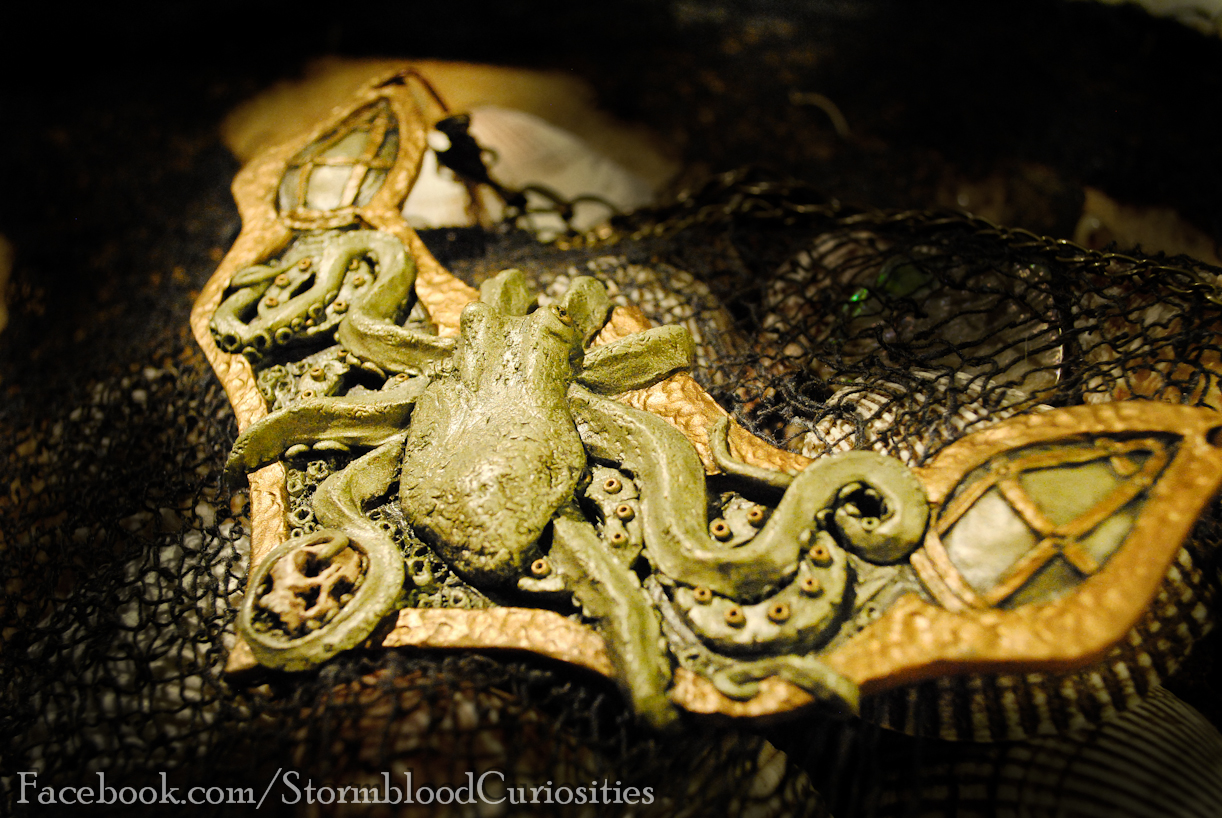 Solid sculpted "wearable art" piece of a nautical theme. An octopus climbing the side of a barnacle-covered vessel while holding a human skull.